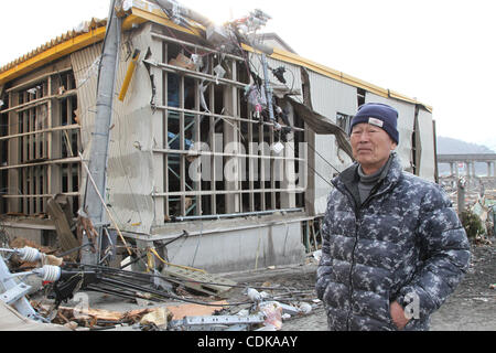 Mar. 14, 2011 - Kamaishi, Japon - l'homme se tient debout devant des maisons effondrées dans Kamaichi, Iwate, Japon. Tremblement de terre de magnitude 9,0 a frappé le nord du Japon. Plusieurs dizaines de milliers de personnes sont toujours portées disparues. (Crédit Image : © Junko Kimura/Jana Press/ZUMAPRESS.com) Banque D'Images