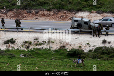 Un jeune Palestinien chevauche son âne cours des soldats israéliens qui monte la garde au cours d'une manifestation contre l'extension de la colonie juive voisine de Halamish dans le village de Nabi Saleh près de Ramallah, samedi, 2 avril 2011. Photo par Issam Rimawi Banque D'Images