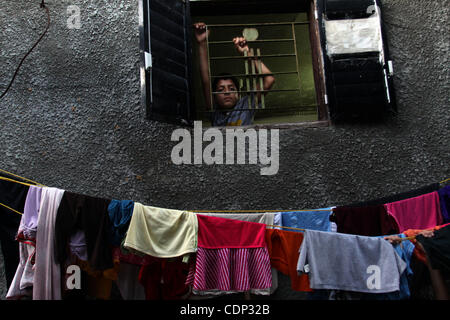 Un garçon palestinien regarde par la fenêtre de sa maison dans le camp de réfugiés de Jabaliya dans le nord de la bande de Gaza le 21 juillet 2011. L'Office de secours et de travaux des Nations Unies (UNRWA) permettra de réduire certains de ses services aux réfugiés palestiniens en raison de déficit budgétaire et de pénurie de fonds des donateurs. Photo par Ali Jad Banque D'Images