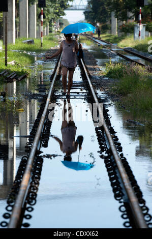 Le 3 novembre 2011 - Bangkok, Bangkok, Thaïlande - un transsexuel thaï est titulaire d'Umbrella et promenades le long des voies de chemin de fer partiellement inondée dans le Lak Si le train est principalement utilisée par les passagers à se rendre à partir de zones inondées au centre de Bangkok. .La Thaïlande connaît ses pires inondations en 50 ans plus de Banque D'Images