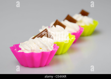 Quatre portions de crème fouettée sur fond blanc. Banque D'Images