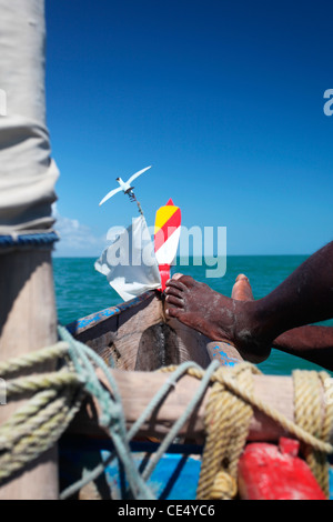 Les pieds d'un pêcheur sur la proue d'une pirogue à voile typiquement malgache, ou pirogue, Canal du Mozambique, Madagascar. Banque D'Images