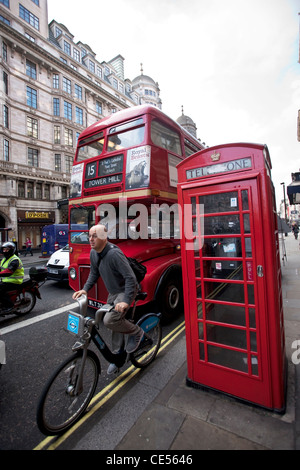 Cycliste à l'avant du Bus Routemaster passant téléphone rouge fort sur le Strand, dans le centre de Londres, Angleterre, Royaume-Uni. Photo:Jeff Gilbert Banque D'Images