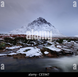 Des roches couvertes de neige et de la rivière qui coule dans Coupall Glencoe avec le pic de distinctif Buachaille Etive Mor's Stob Dearg derrière Banque D'Images