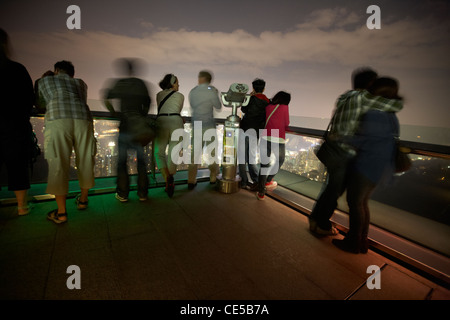 Les touristes regarder vers le bas sur hong kong à partir de la terrasse sky au sommet de Hong Kong Chine Asie flou délibéré Banque D'Images