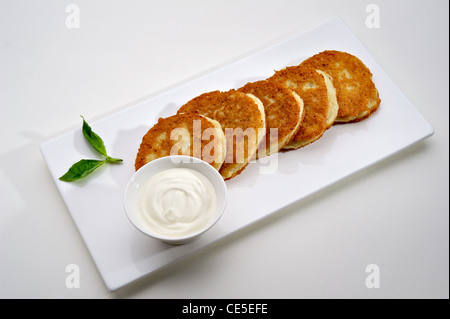 Crêpes aux pommes de terre sur la plaque blanche avec de la crème Banque D'Images