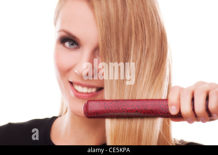 Femme à l'aide d'un fer à lisser ses cheveux blonds Banque D'Images