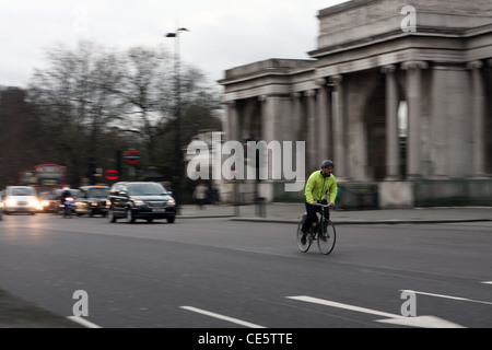 Un cycliste en face de trafic de passage autour de Hyde Park Corner à Londres, un soir Banque D'Images