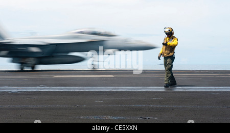 Maître de Manœuvre Aviation 2e classe Roberto Andiarena vérifie le temps qu'un F/A-18F Super Hornet de la Black Aces of Strike Fighter Squadron 41 lance sur le poste de pilotage de la classe Nimitz porte-avions USS John C. Stennis, 23 janvier 2012 dans la mer de Chine du Sud Banque D'Images