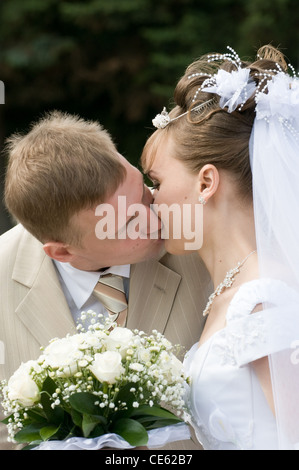 Les jeunes mariés s'embrasser après la cérémonie du mariage Banque D'Images