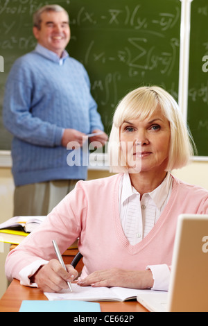 Portrait de blonde female looking at camera with senior man on background Banque D'Images