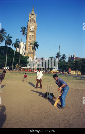 Les garçons à jouer au cricket sur le sol et Rajabhai tour en arrière-plan ; Bombay Mumbai Maharashtra ; Inde ; Banque D'Images