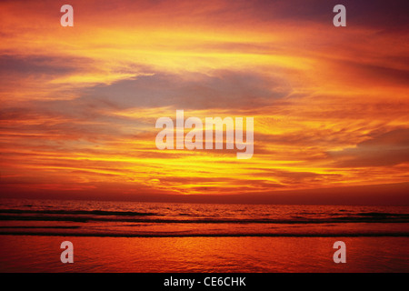 Les tons de jaune orange rouge nuages chaud ciel et mer après le coucher du soleil ; plage de Juhu Mumbai Bombay ; ; ; Inde Maharashtra Banque D'Images