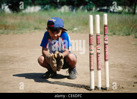 Enfant indien jouant au cricket faisant du cricket en restant assis derrière des souches ; Inde ; Asie ; MR#158 Banque D'Images