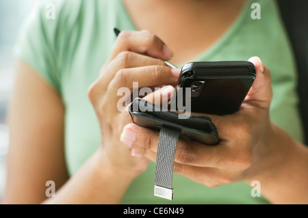 Gros plan d'une femme à l'aide de son smartphone, avec les deux main tenant. Banque D'Images