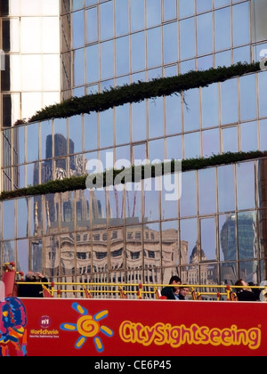 Un bus de tourisme sur le pont de Londres, avec un reflet de la ville dans une fenêtre de bureau à proximité. Banque D'Images