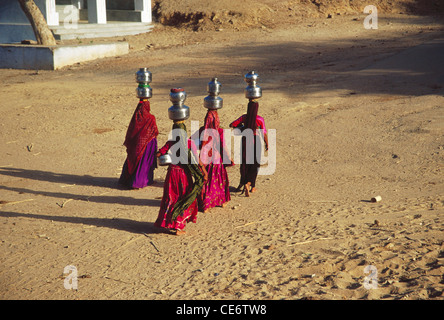 Quatre femmes indiennes équilibrant portant des pots d'eau métalliques à la tête Kutch Gujarat Inde Asie Banque D'Images