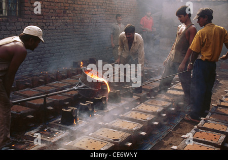 Les hommes qui versent de la fonte liquide dans la fonderie de fonte ; rajkot ; gujarat ; inde ; asie Banque D'Images