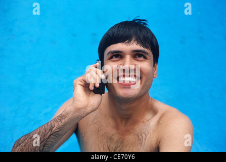 RHS 84016 : South Asian Indian man heureux piscine bain douche téléphone mobile sans fil PARLER MR Banque D'Images