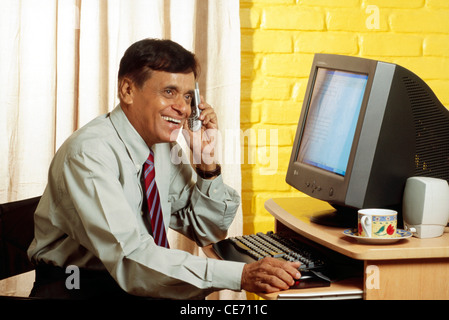 VEP 84047 : South Asian Indian old man active parler d'ordinateur de bureau mobile phone tasse café thé MR# 448 Banque D'Images