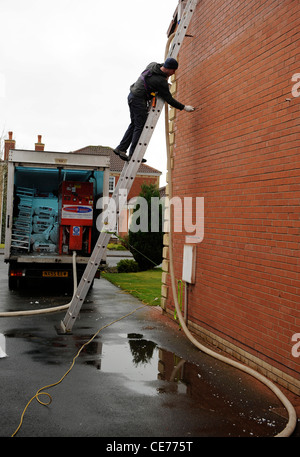 L'isolation des murs creux. Un ouvrier souffle matériau isolant à la cavité du mur de la propriété résidentielle écoénergétique maison Banque D'Images