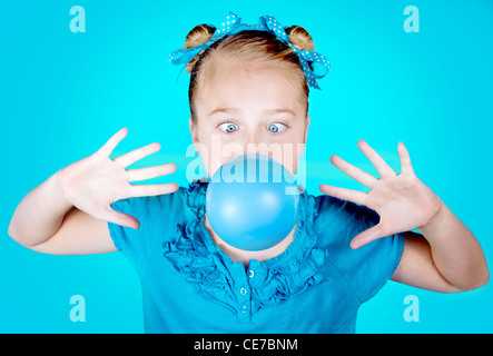 Un cross eyed girl wearing blue avec les yeux bleus et le blue bow, soufflant une bulle bleue. Sur un fond bleu Banque D'Images