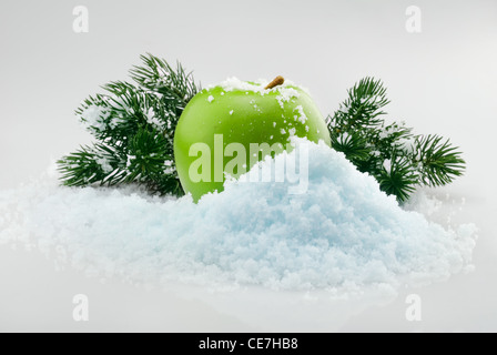 Délicieux vert pomme de Noël dans la neige avec des branches d'arbre de Noël sur l'arrière-plan Banque D'Images