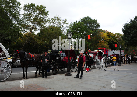 Les arbres d'automne voir calèches, deux pilotes top hat standing trottoir, Grand Army Plaza, Central Park South, New York Banque D'Images