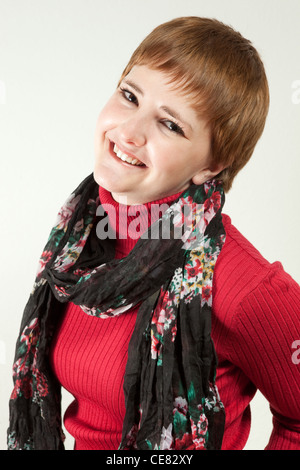 Heureux jeune rousse femme portant un col roulé et un foulard, dans le studio Banque D'Images