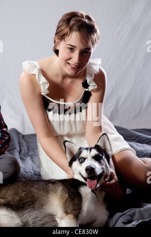 Pretty Caucasian woman avec son animal de compagnie chien Husky, assis sur le plancher et en jouant avec le chien Banque D'Images