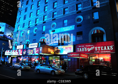 Vue de nuit, vers la 7e Avenue, immeuble lumineux bleu, TGI Friday's Restaurant, Tad's Steakhouse, West 50th Street, New York Banque D'Images