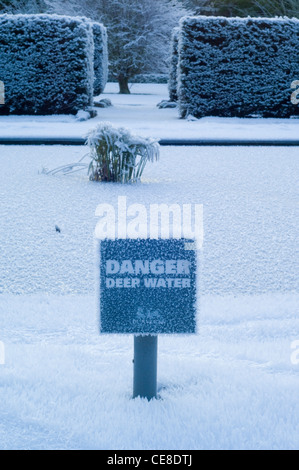 De gros cristaux de givre sur un danger de profondeur de l'eau signe par la glace d'un étang gelé, dans le jardin de Dunvegan Castle Banque D'Images