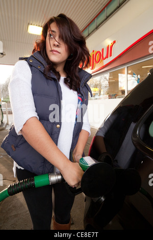 Adolescente remplir sa voiture avec de l'essence sans plomb à une station service, UK Banque D'Images