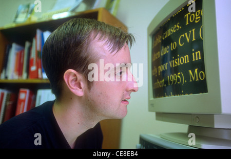 Personnes ayant une lecture élargie de l'homme spécialement type sur l'écran d'ordinateur, Hindhead, Surrey, UK. Banque D'Images