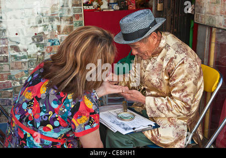 Les gens obtenant leurs paumes pour lire leur fortune par Leo au calembour Il Fortune Lectures à Los Angeles, Chinatown. Banque D'Images