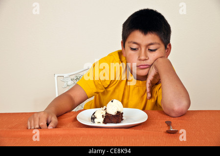 10-11 ans Hispanic boy ne veut pas manger assis à table la diversité raciale multi multiculturelles la diversité raciale Monsieur © Myrleen Pearson Banque D'Images