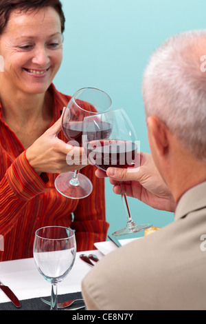 Photo d'un couple dans un restaurant toasting leurs verres de vin rouge, Banque D'Images