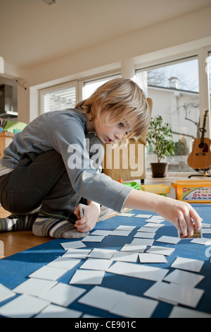 Garçon jouant le jeu de cartes mémoire sur le sol. Banque D'Images