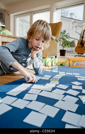 Garçon jouant le jeu de cartes mémoire sur le sol. Banque D'Images