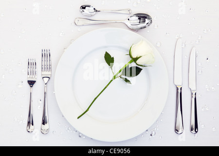 Photo d'un endroit de la table avec une rose blanche sur la plaque. Banque D'Images