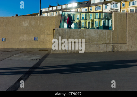 Deux femmes marchant sur la promenade de Bridlington, East Riding of Yorkshire, UK avec deux figures de l'ombre en diagonale Banque D'Images