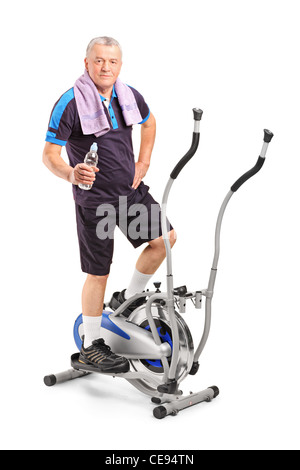 Senior man holding une bouteille d'eau et debout sur une machine elliptique Banque D'Images