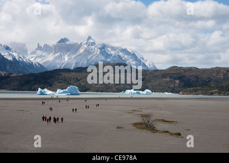 Les touristes à pied vers la rive du lac Grey pour voir les icebergs dans l'eau de glacier gris, avec les montagnes derrière Banque D'Images