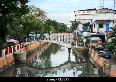 Les gens qui marchent avec des vélos sur le petit pont sur le canal des bidonvilles à Bangkok Banque D'Images