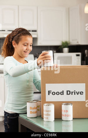 États-unis, Illinois, Metamora, Smiling girl (10-11) mettre la nourriture en boîte en carton dans la cuisine Banque D'Images