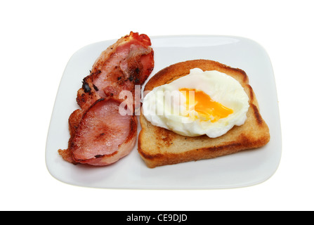 L'œuf poché avec un écoulement jaune sur pain frit avec du bacon dans une assiette blanche contre isolés Banque D'Images