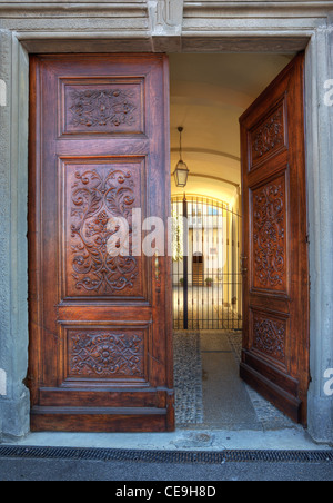 Image orientée verticale Porte en bois ouvragé à l'entrée de la petite cour de la ville de La Morra, au nord de l'Italie. Banque D'Images