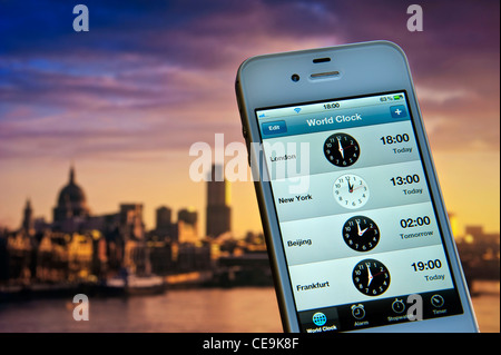 Smartphone iPhone écran affichage des fuseaux horaires à Londres New York et Pékin Francfort avec City de Londres et la Tamise derrière Banque D'Images