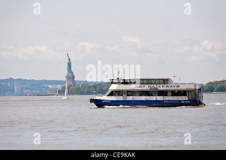 Un ferry transporte les passagers de New York sur la rivière Hudson et passant devant la Statue de la liberté. Banque D'Images