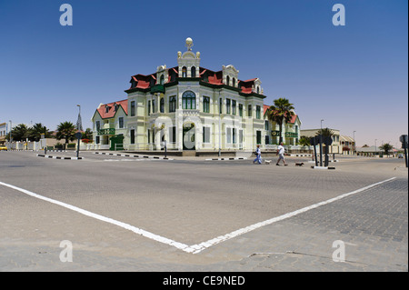 Vieux couple avec leurs chiens qui traversent la rue en face de l'dans Swakopmund Hohenzollernhaus, Namibie Banque D'Images